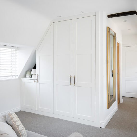 Elegant attic conversion in the Cotswolds featuring exposed beams, soft layered textures, and natural light—interior design by a Cotswolds-based designer.
