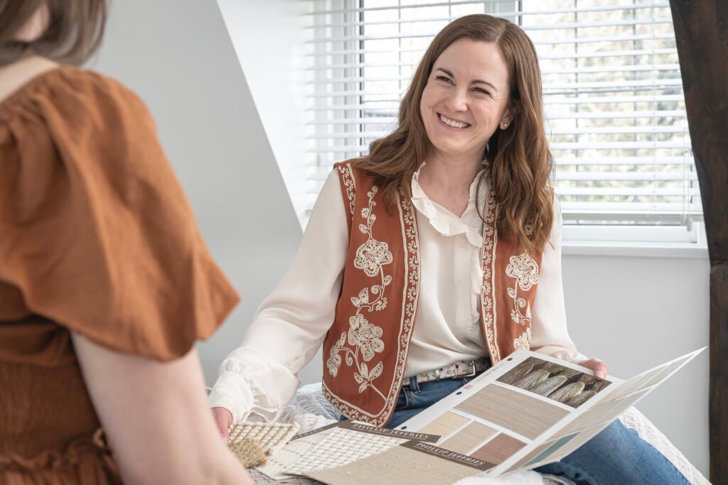Interior designer holding material samples during an in-home consultation, discussing finishes and design choices with a client