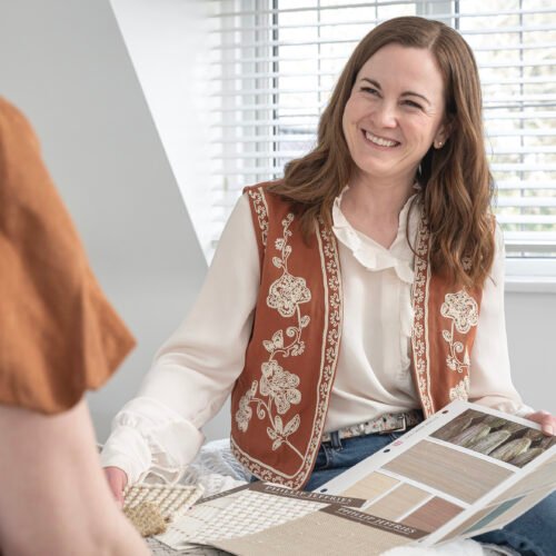 Interior designer holding material samples during an in-home consultation, discussing finishes and design choices with a client